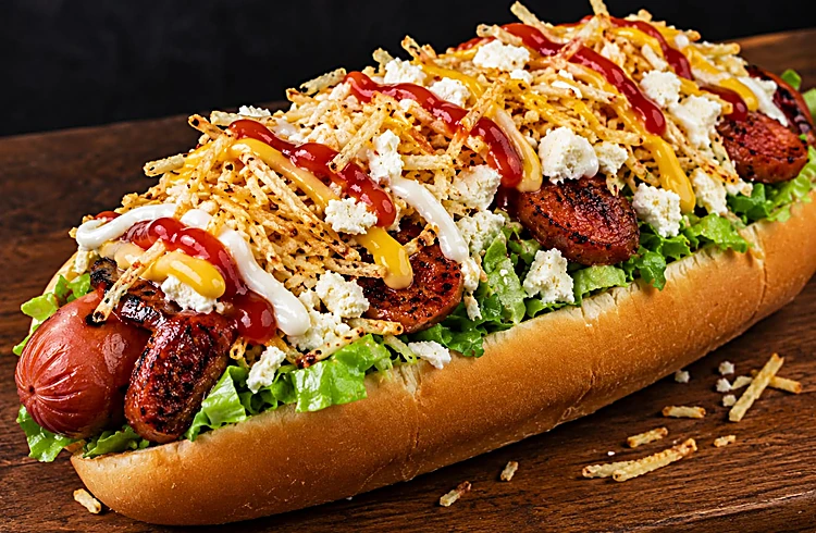 Hot dog cargado con lechuga, papas ripio, queso y salsas